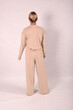 © Шамиль Алиев - A young girl in beige home clothes on a white background in the studio is standing with her back