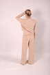 © Шамиль Алиев - A young girl in beige home clothes on a white background in the studio is standing with her back