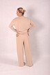 © Шамиль Алиев - A young girl in beige home clothes on a white background in the studio is standing with her back