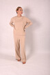 © Шамиль Алиев - A young girl in beige home clothes on a white background in the studio