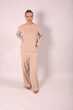 © Шамиль Алиев - A young girl in beige home clothes on a white background in the studio