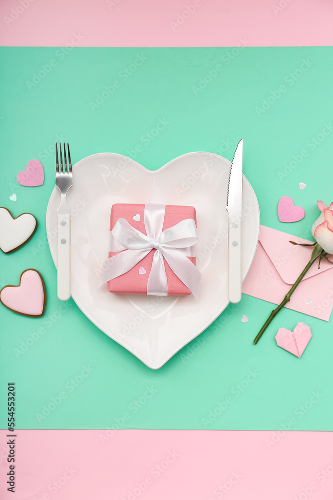 Table setting for Valentine's Day with gift, envelope and rose on green background
