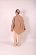 © Шамиль Алиев - A young girl in beige home clothes on a white background in the studio is standing with her back