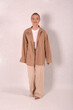 © Шамиль Алиев - A young girl in beige home clothes on a white background in the studio