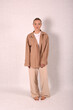 © Шамиль Алиев - A young girl in beige home clothes on a white background in the studio