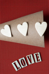 Wall Mural - out of focus cardboard cone with three wooden hearts and the word love on red corrugated paper