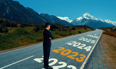 The 2023 New Year journey and future vision concept . Businessman traveling on highway road leading forward to happy new year celebration in beginning of 2021 for fresh and successful start .