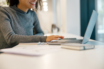 Wall Mural - Smiling woman freelancer working laptop and making notes while sitting near windows in cozy cafe