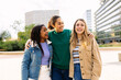 © Xavier Lorenzo - Three happy multiracial young women laughing outdoors. United female best friends having fun walking in city street. Community and international friendship concept
