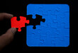 © Maxim Chuev - one hand connecting puzzles on black background.carton puzzle. Teamwork, partnership, business idea, cooperation management concept. one 1 red missing puzzle.