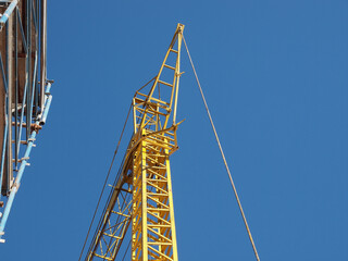 Wall Mural - yellow tower crane and scaffolding over blue sky