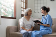 Asian senior woman patient on sofa with medical doctor woman wearing stethoscope diagnosis
