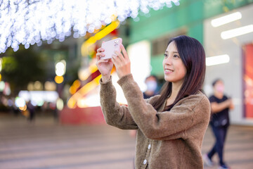 Wall Mural - Woman take photo on mobile phone in city at night