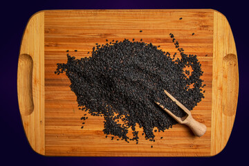 Wall Mural - Black sesame seeds on a wooden kitchen board. Healthy food concept.