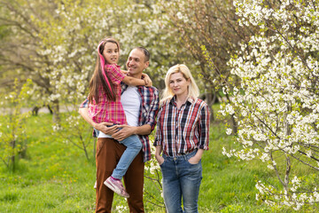 Wall Mural - Happy family spending good time together in spring in a flowering garden