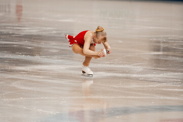 Wall Mural - 
a little girl in a red dress participates in a figure skating competition