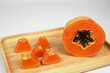 half of ripe papaya fruit with seeds on wooden board .