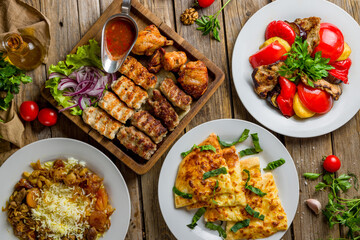 Poster - platter of different kebabs, pilaf with beeg, khachapuri with cheese, adjabsandali top view on wooden table