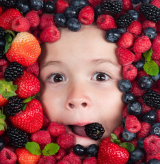 Healthy food for kids. Assorted mix of strawberry, blueberry, raspberry, blackberry background. Berries closeup near kids face. Fresh berries, top view. Mix of raw fresh berries fruits.