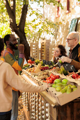 Wall Mural - Young happy African guy tasting apple before purchasing while shopping for natural organic products at local farmers market. Black man customer enjoying food tasting while buying fresh local produce