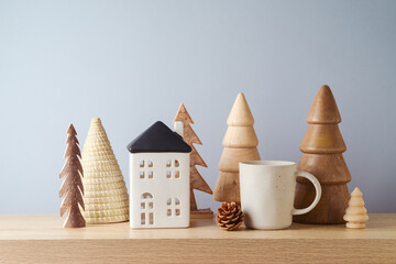 Wall Mural - Wooden Christmas trees, coffee cup and house composition on table over gray wall background. Sustainable Christmas decoration concept.