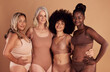 © David L/peopleimages.com - Beauty, diversity and women in lingerie hug in studio isolated on a brown background. Portrait, underwear or body positive group of friends in makeup or cosmetics embrace for self love or empowerment