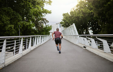 Wall Mural - Fitness, man and running in the city park for healthy exercise, cardio workout or training in the outdoors. Active athletic male runner in sports activity, run or exercising outside on city bridge
