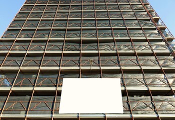 Blank information board hanging on the scaffoldings of the palace facade under construction. Bottom view with street light in the center. Background for copy space.