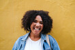 © Westend61 - Happy young woman with curly hair in front of yellow wall
