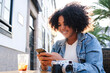 © Westend61 - Happy woman using smart phone sitting in cafe