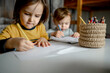 © Westend61 - Boy with brother drawing on paper by colored pencils in jute container
