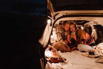 Happy young white couple smiling and lying together in car outdoors