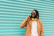 © Renata Hamuda - smiling african american man in dreadlocks with stylish sunglasses with headphones around his neck on blue background talking by mobile phone