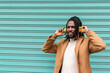 © Renata Hamuda - stylish african american man in dreadlocks smiling and listening music with yellow headphones on blue background