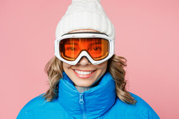 Close up snowboarder smiling happy woman wear blue suit goggles mask hat ski padded jacket look camera isolated on plain pastel pink background. Winter extreme sport hobby weekend trip relax concept.