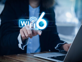 Wi-Fi 6 speed logo glowing on virtual screen while businesswoman pointing hand and using laptop computer. Wifi6 technology new generation telecommunications connectivity network by smart performance.