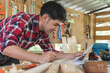 © Pormezz - person doing diy project at home. Man measuring wood to doing cabinet craftworks as a hobby.