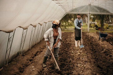 Shot of a young female farmer working with her husbant in their greenhouse.