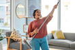 © Jordan C/peopleimages.com - Dance, radio or woman cleaning with music for singing or listening to a song with broom as a guitar at home. Relax, freedom or happy Indian girl cleaner streaming audio on headphones or housekeeping