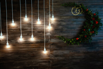 Glowing light bulbs hang on a long cord against the background of a wooden wall