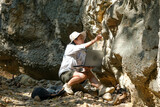 Fototapeta Uliczki - Female geologist using laptop computer examining nature, analyzing rocks or pebbles. Researchers collect samples of biological materials. Environmental and ecology research.
