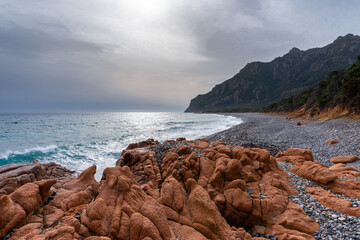 Poster - rugged coast in Sardinia with waves crashing onto the rocky beach and red granite boulders in the foreground