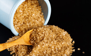 Wall Mural - Scattered yellow sea salt, sea salt in a jar and sea salt in a wooden spoon. Black background