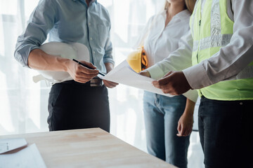 Cropped view of team engineers checking new construction project blueprints with engineering tools at work desk in office