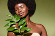 © Beauty Agent Studio - Organic cosmetics concept.  Beauty portrait of young beautiful african american woman with posing with a green branch, model curly hair against green background.