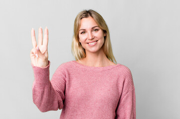 caucasian blonde woman smiling and looking friendly, showing number three