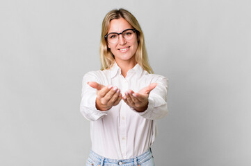 Wall Mural - caucasian blonde woman smiling happily with friendly and  offering and showing a concept