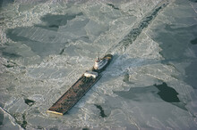 Tugboat Pushing Barge Through Winter Ice On The Chesapeake Bay.; CHESAPEAKE BAY, MARYLAND.