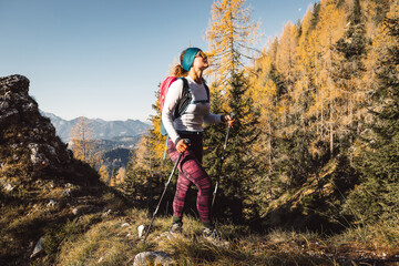 Canvas Print - Cheerful caucasian woman hiking on a sunny autumn day, soaking in the mountain sun 