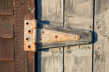 Close-up Of An Old Rusty Hinge On A Wooden Door; Cortland, Nebraska, United States Of America
